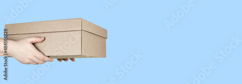 Large cardboard box in hands on blue background