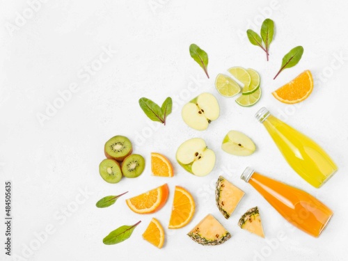 Healthy food. Drinks in a glass bottle sliced ​​fruits kiwi, orange, pineapple, apple, lime on a light background.