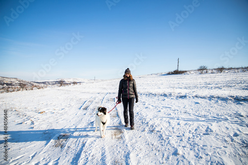 woman and her happy white dog enjoying winter snow outdoors on sunny day