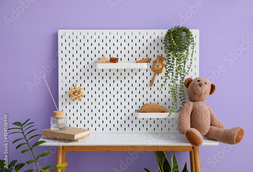 Table with pegboard and toys near lilac wall photo