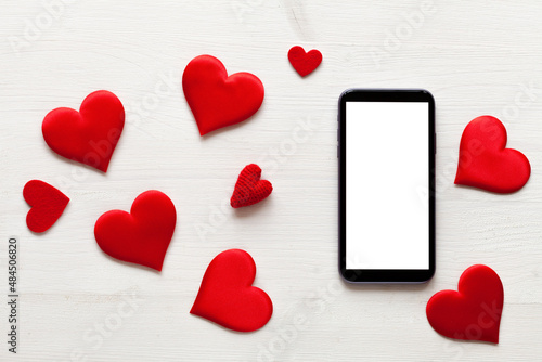 White wood background with red hearts symbol and a tablet, love concept, top view