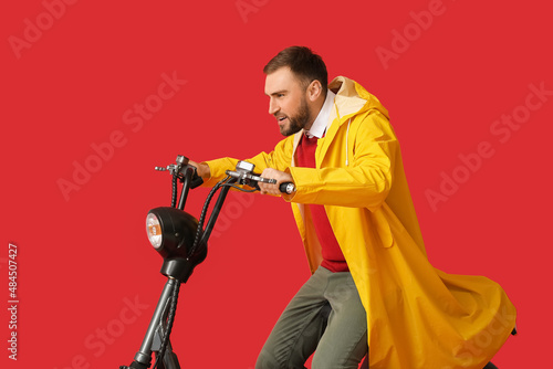 Young man in raincoat ridin...