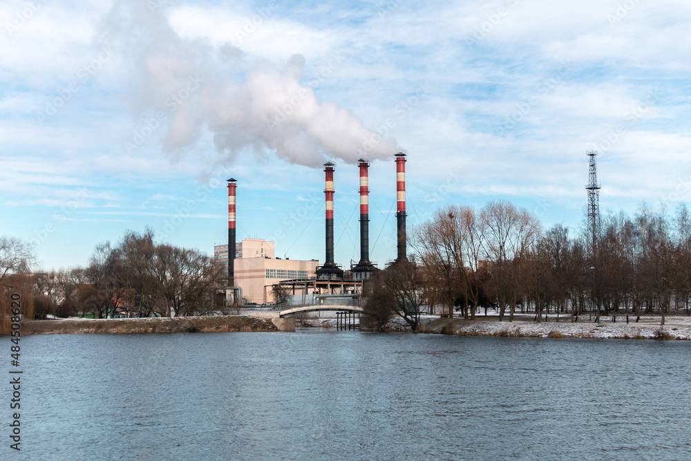 Factory chimneys emit puffs of smoke against the blue sky. The concept of air pollution, environment, industry and ecology, global warming. Factory chimneys emit puffs of smoke against the blue sky. The concept of air pollution, environment, industry and ecology, global warming.