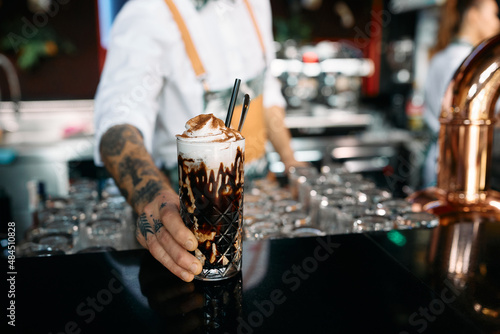Close-up of bartender serves iced coffee at bar counter.