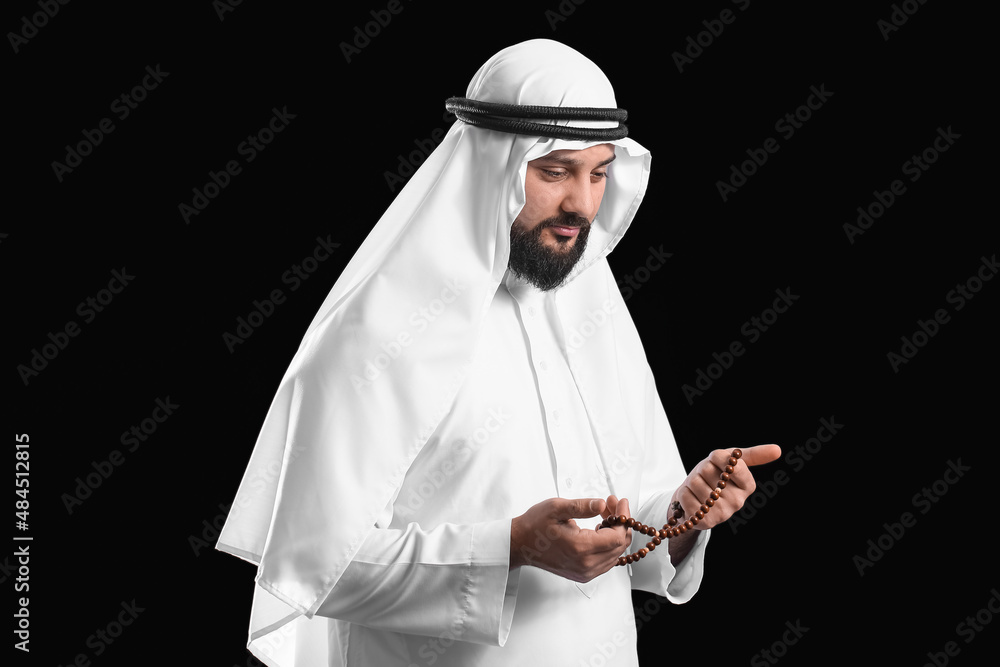 Muslim man with prayer beads on black background Muslim man with prayer beads on black background