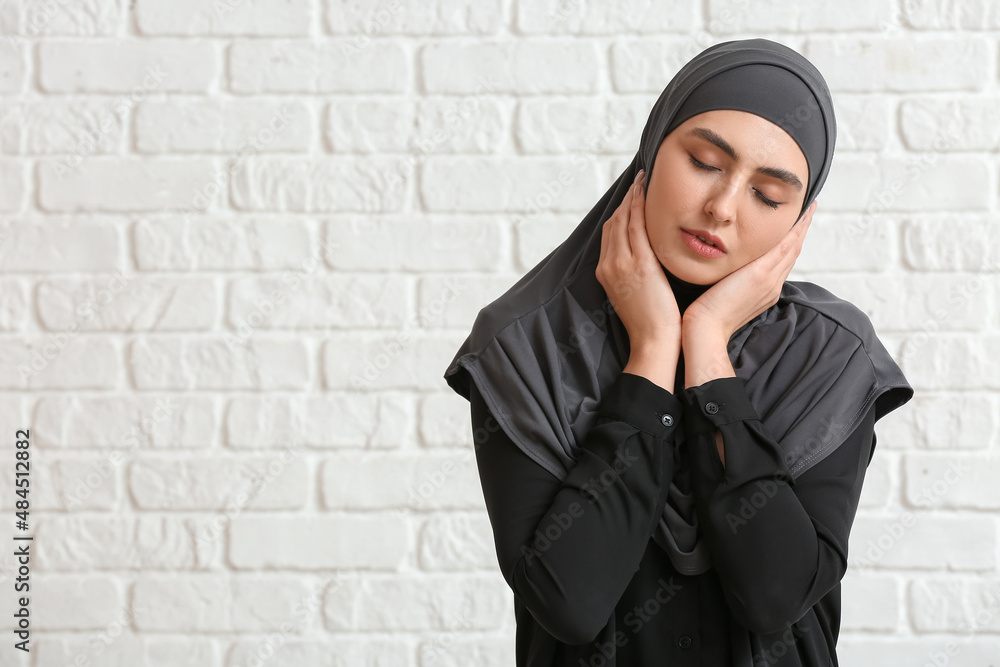 Naklejka premium Beautiful Muslim woman on white brick background