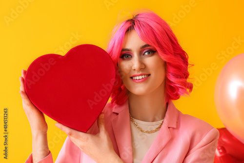 Stylish woman with bright hair and gift on color background. Valentine s Day celebration