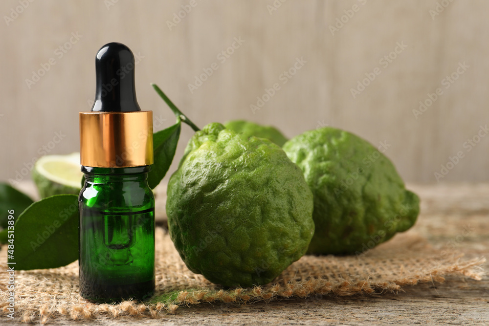 Bottle of essential oil and fresh bergamot fruits on table - obrazy, fototapety, plakaty 