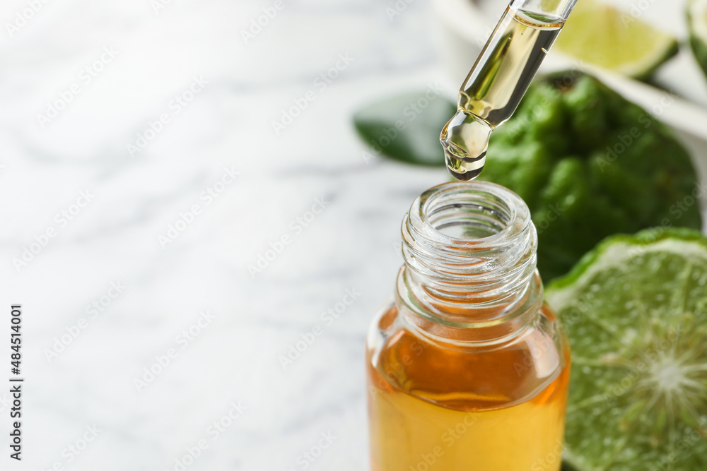 Bergamot essential oil dripping from pipette into bottle on table, closeup. Space for text Bergamot essential oil dripping from pipette into bottle on table, closeup. Space for text