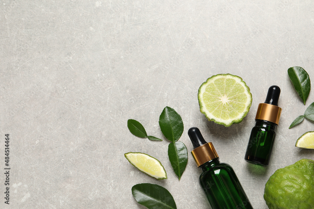 Glass bottles of bergamot essential oil and fresh fruits on light table, flat lay. Space for text - obrazy, fototapety, plakaty 