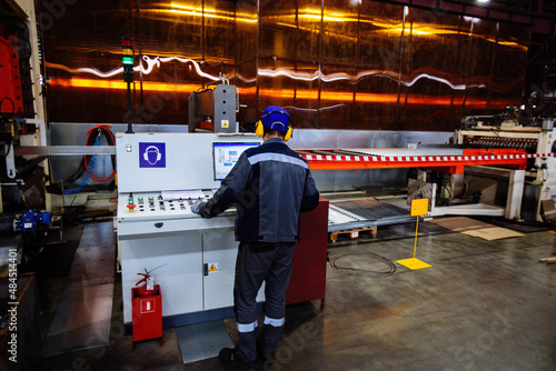 Factory worker operating CNC machine in metalworking workshop
