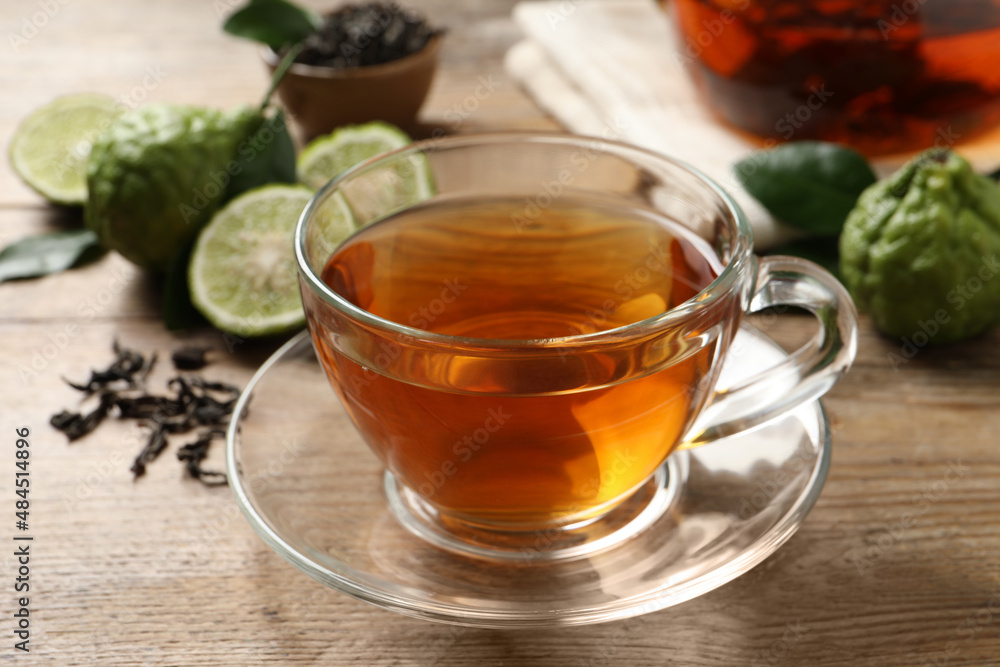 Glass cup of tasty bergamot tea and fresh fruits on wooden table, closeup Glass cup of tasty bergamot tea and fresh fruits on wooden table, closeup