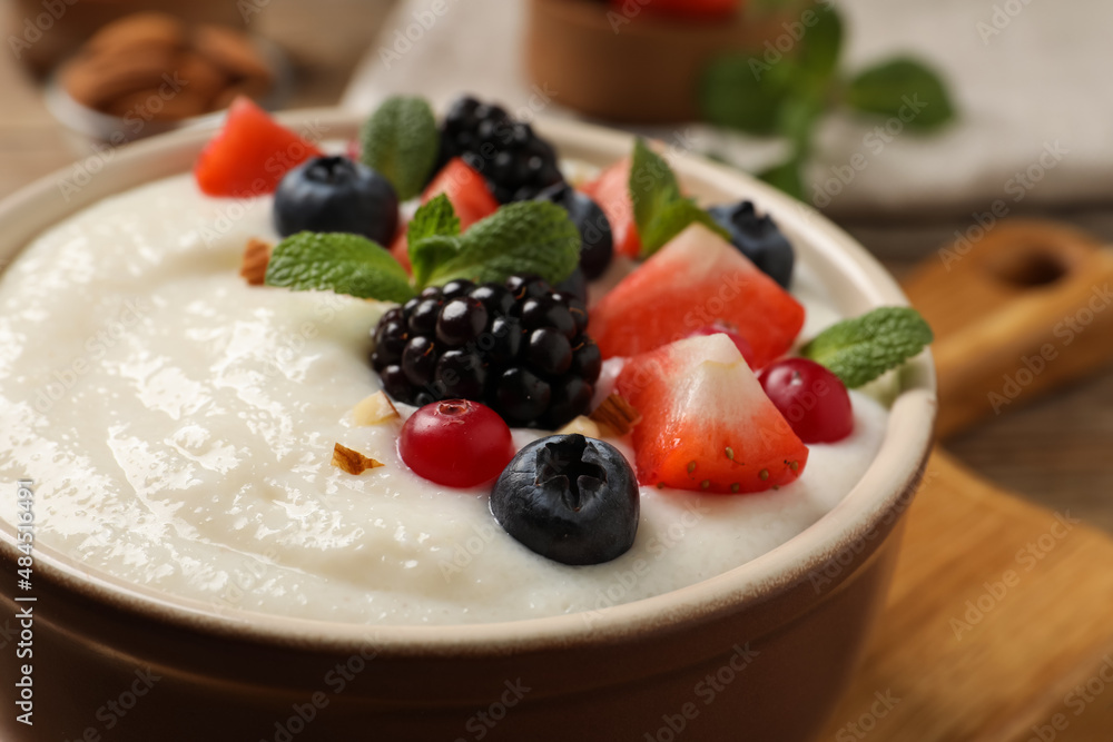 Delicious semolina pudding with berries in bowl on table, closeup