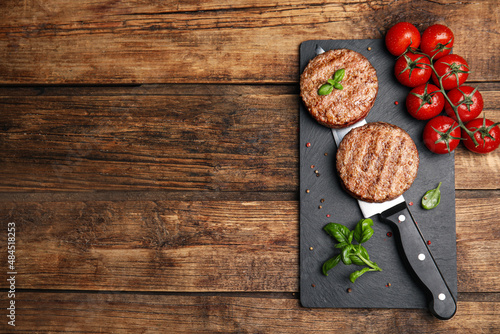 Tasty grilled hamburger patties served on wooden table, flat lay. Space for text