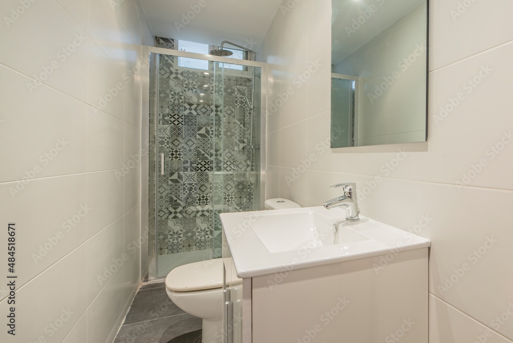 Bathroom decorated in a contemporary style with a shower wall covered with hydraulic tiles, a white vanity unit and a frameless glass mirror Bathroom decorated in a contemporary style with a shower wall covered with hydraulic tiles, a white vanity unit and a frameless glass mirror