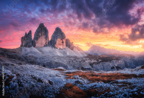 Mountains and beautiful sky with colorful clouds at sunset. Summer landscape with mountain peaks, stones, grass, trails, violet sky with pink clouds. High rocks. Tre Cime in Dolomites, Italy. Nature