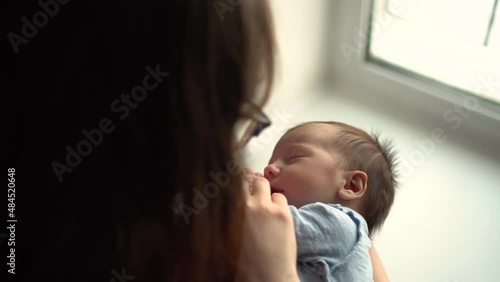 A young mother holds a child in her arms against the background of a window. View from above. photo