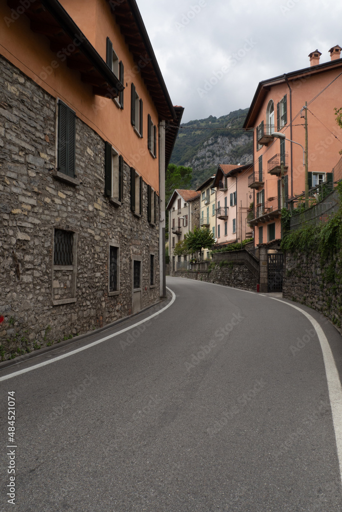 Curvy empty road in small village countryside of lake como, italy with orange houses