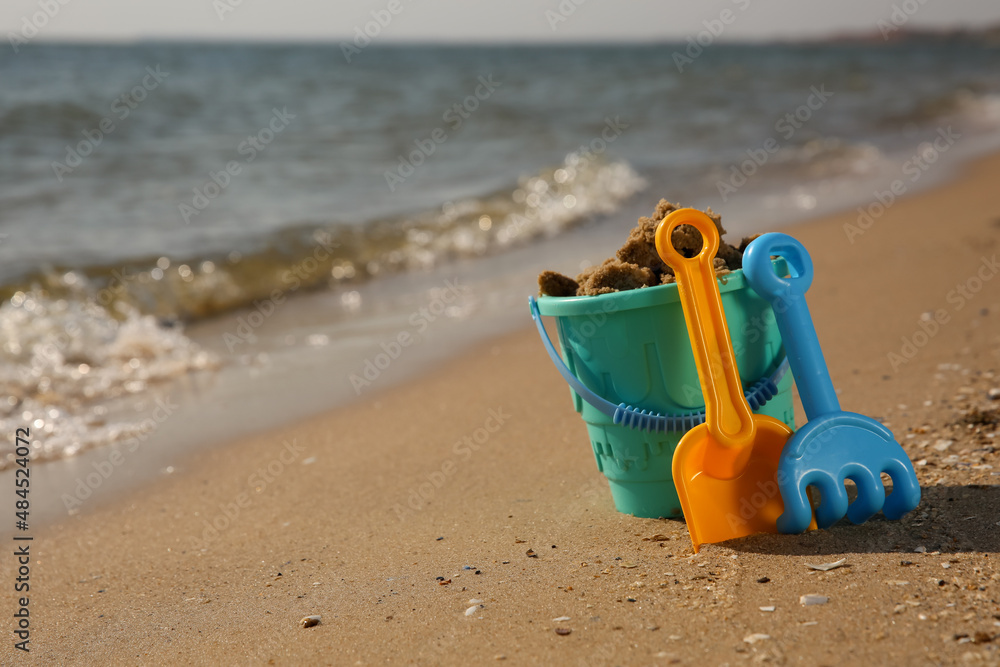 Set of plastic beach toys on sand near sea, space for text. Outdoor play Set of plastic beach toys on sand near sea, space for text. Outdoor play