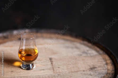 Glencairn glass with whiskey on bourbon barrel photo