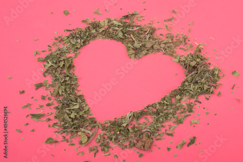 crushed marijuana heart shape on a pink background holiday valentine for cannabis lovers