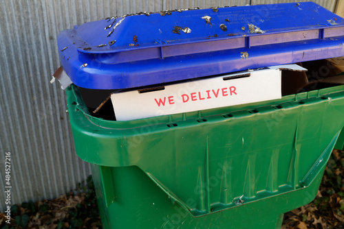 WE DELIVER pizza box inside bleu and green plastic trash can cover in disgusting bird droppings. © Noel