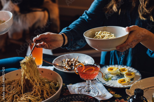 woman serving herself spaghetti noodles over table full of food photo