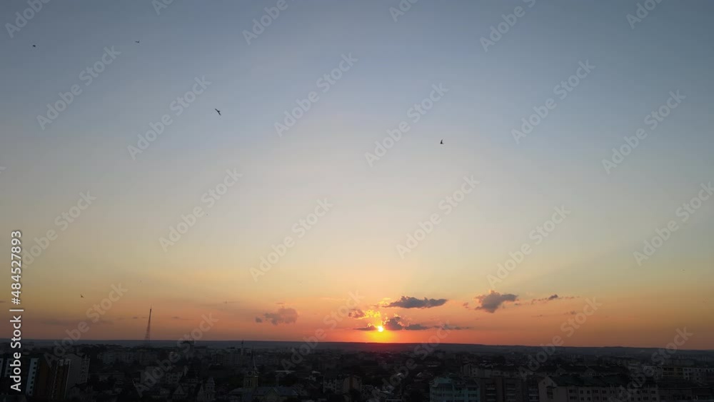 Bright colorful sunset sky with rays of sunlight and flock of birds flying against setting sun Bright colorful sunset sky with rays of sunlight and flock of birds flying against setting sun