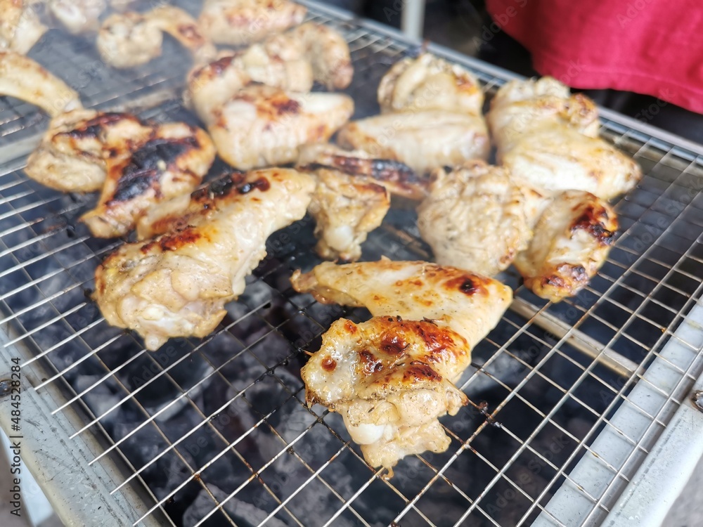 Close up photo of chicken wing meat on grill.