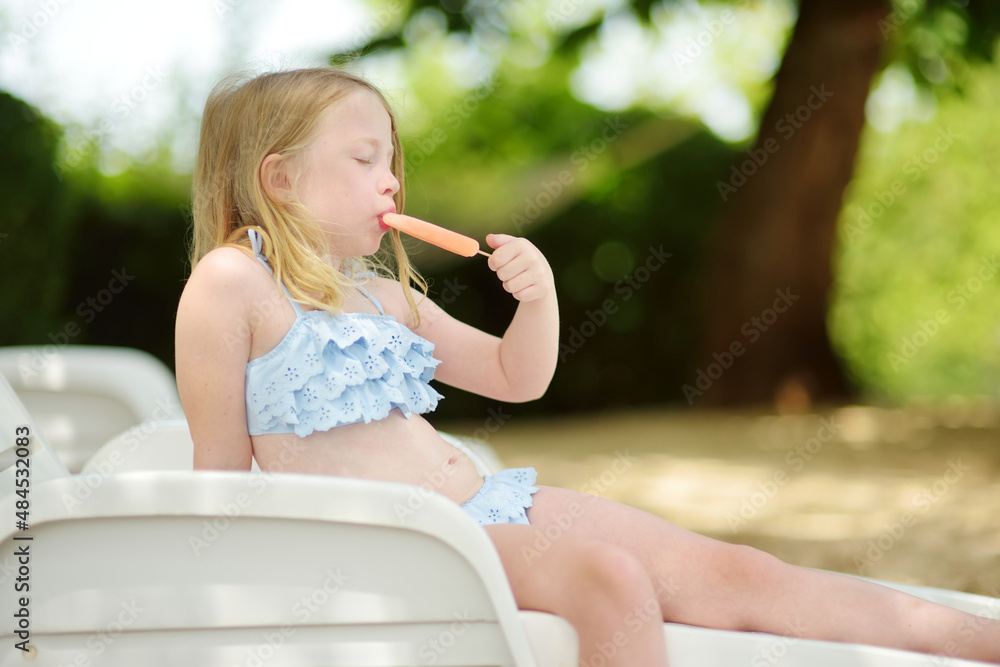 little girl sexy Cute young girl in a swimsuit having an ice cream by outdoor pool. Child having fun on hot summer day. Kid eating gelato on family vacations in Italy. Stock 写真 | Adobe