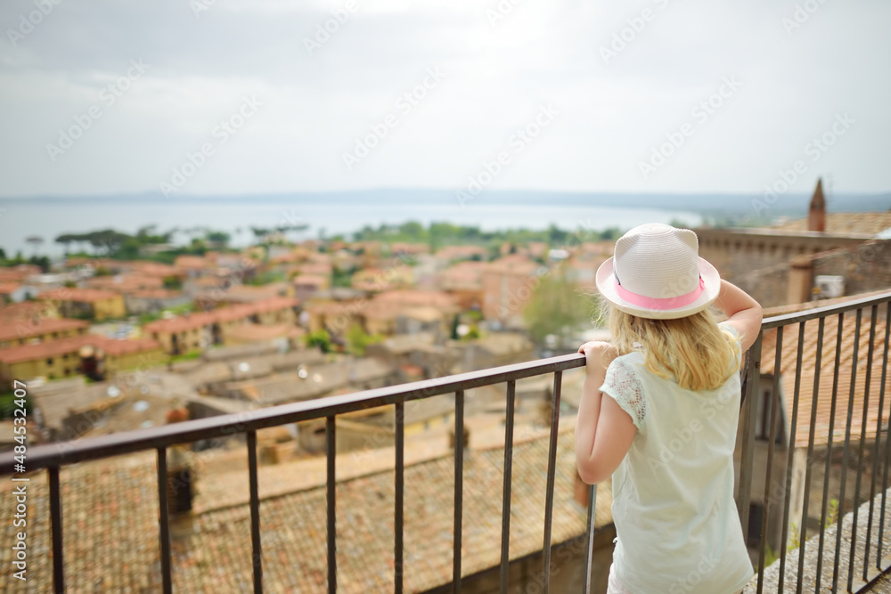 Young girl exploring medieval streets of picturesque resort town Bolsena, situated on the shores of Italy's largest lake, Lago Bolsena, Italy.