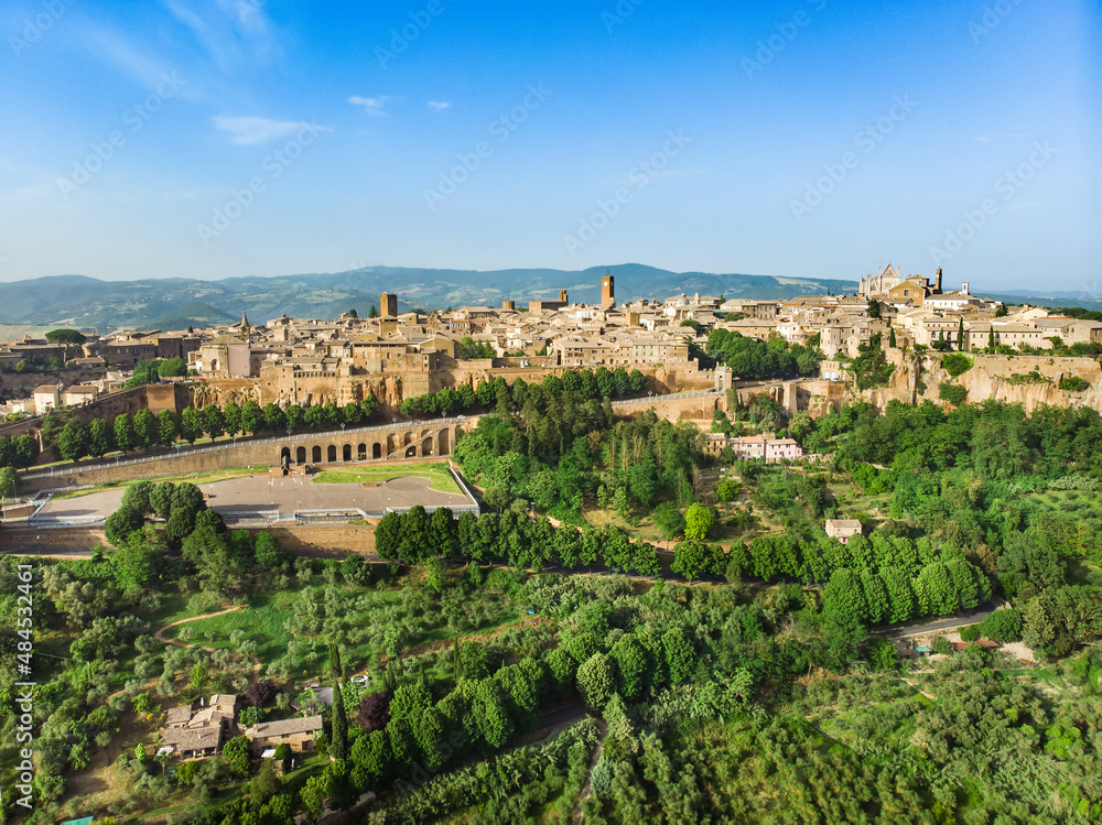 Aerial view of the famous Orvieto, a medieval hill town, rising above the almost-vertical faces of tuff cliffs and surrounded by its vineyards and wineries, Italy.