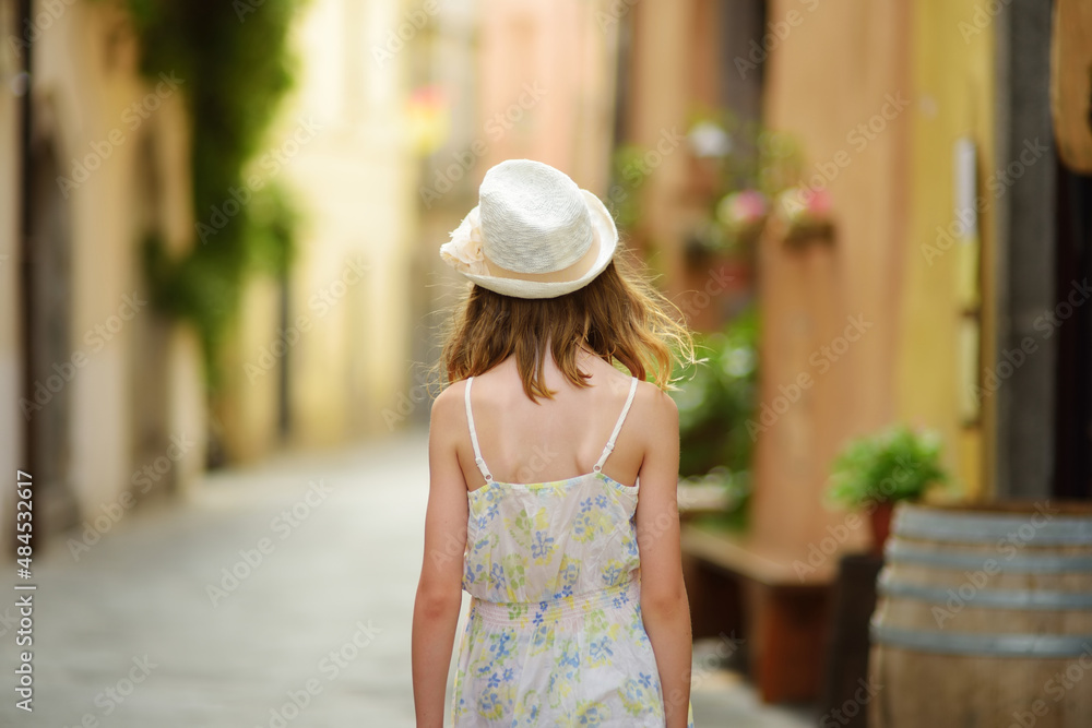 Young girl exploring medieval streets of picturesque resort town Bolsena, situated on the shores of Italy's largest lake, Lago Bolsena, Italy.