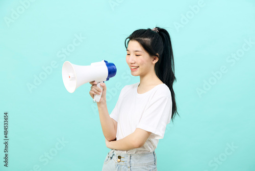 Asian woman holding megaphone on blue background
