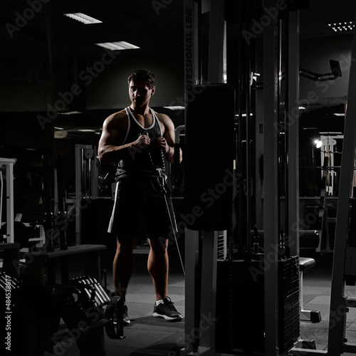Muscular athletic bodybuilder fitness model posing after exercises in gym