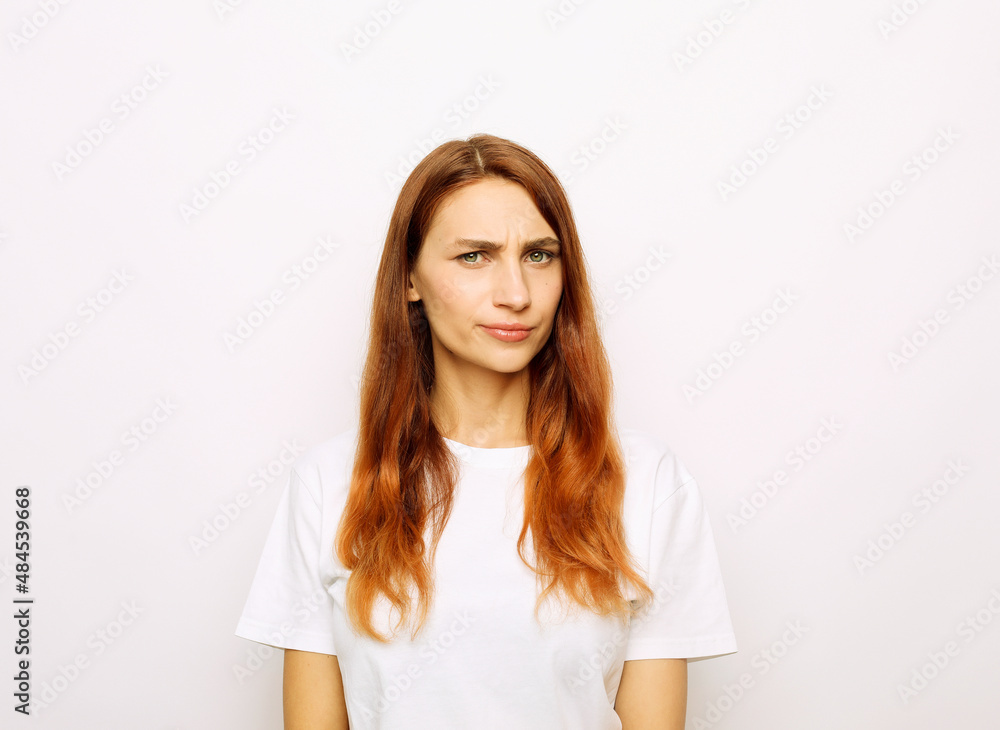 Young beautiful redhead woman wearing white t-shirt over white background skeptic and nervous Young beautiful redhead woman wearing white t-shirt over white background skeptic and nervous