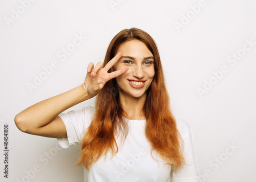 cheerful excited woman with long red hair showing peace sign