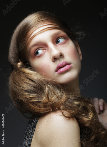 Blonde female with curly hairstyle and pink lips.