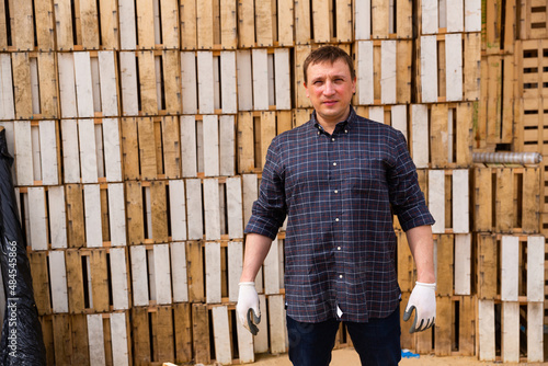 Portrait of positive worker standing against the background of wooden boxes