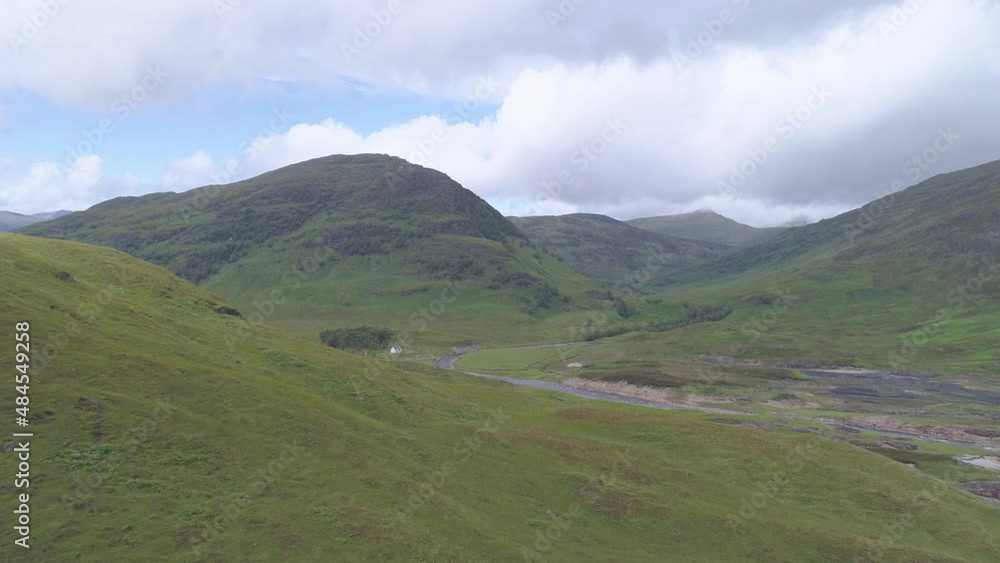 Aerial reveal shot over some hills to a stone cottage at the base of a mountain on Rannoch Moor near Loch Treig Aerial reveal shot over some hills to a stone cottage at the base of a mountain on Rannoch Moor near Loch Treig