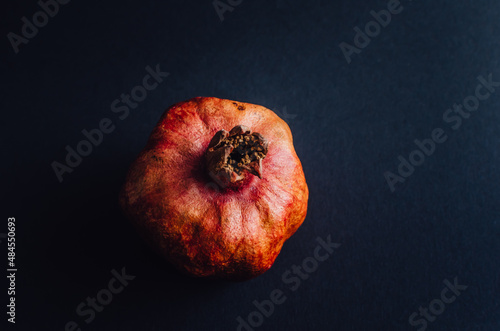 Dried red garnet on a dark background, rough texture of the peel of the fruit. space for text