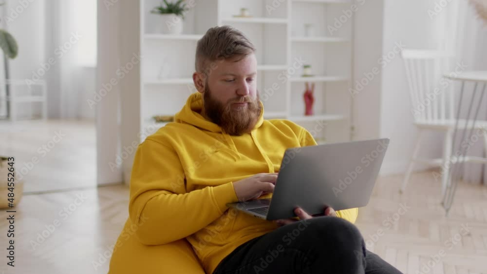 Freelancer Guy Using Laptop Working Online In Beanbag Chair Indoor Freelancer Guy Using Laptop Working Online In Beanbag Chair Indoor