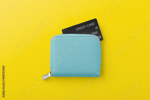 Blue wallet with black credit card on yellow background