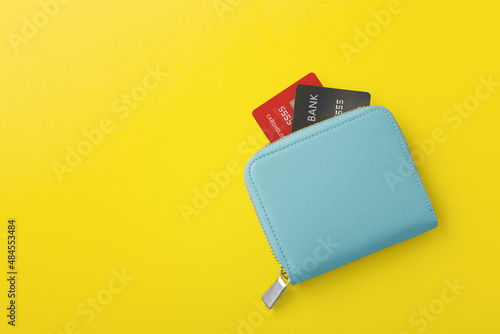 Blue wallet with credit card on yellow background