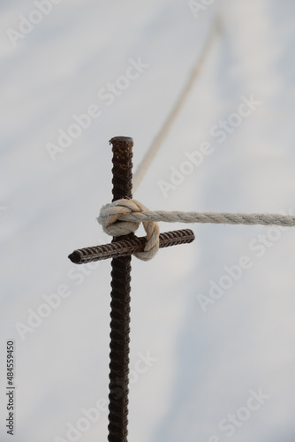 t shaped cross shaped metal rebar post with rope tied in knot around top for support for fenced off safety area in winter vertical format room for type white background religious symbol religion tied 