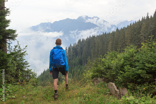 Panorama view with male hiker man in rainwear standing in front of alpine mountains and clouds in Salzburgerland, Austria © johannes86