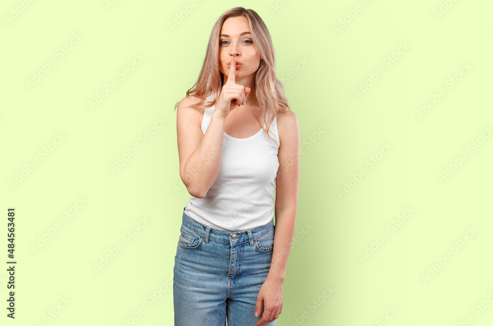 Portrait of young woman asking to be quiet with finger on lips isolated on color background Portrait of young woman asking to be quiet with finger on lips isolated on color background