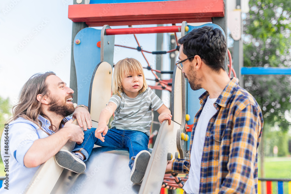 boy on top of a slide playing with his dads. boy on top of a slide playing with his dads.