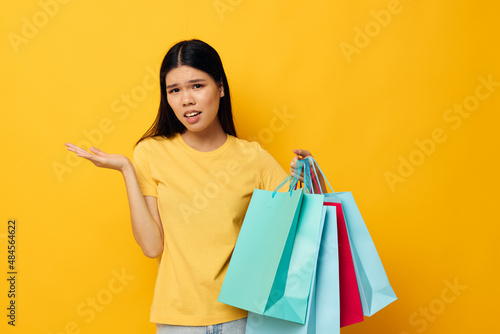 woman with Asian appearance in a yellow T-shirt with multicolored shopping bags studio model unaltered