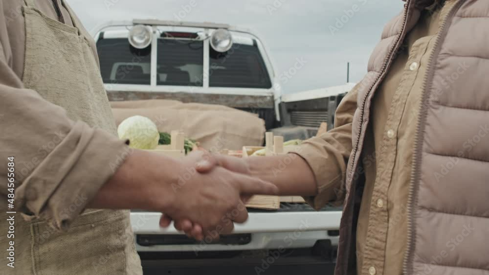 Unrecognizable woman buying vegetables at farmers standing in front of farm owner discussing something and doing handshake Unrecognizable woman buying vegetables at farmers standing in front of farm owner discussing something and doing handshake